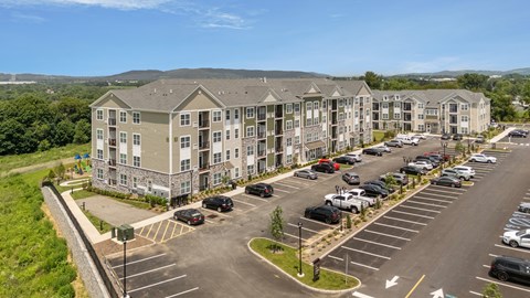 A parking lot in front of a large apartment complex.