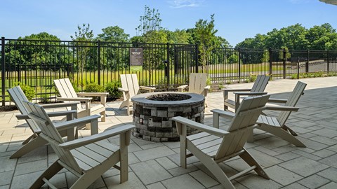 A fire pit surrounded by chairs in a sunny outdoor setting.