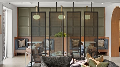 A living room with a grey couch and a glass partition.