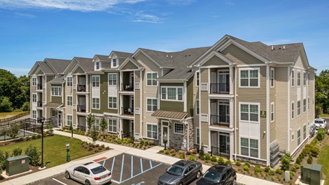 A large apartment complex with a parking lot in front.