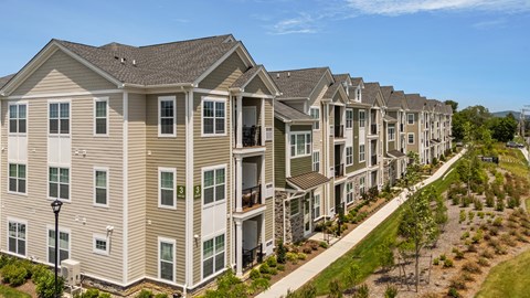 A row of modern townhouses with balconies and greenery in front.