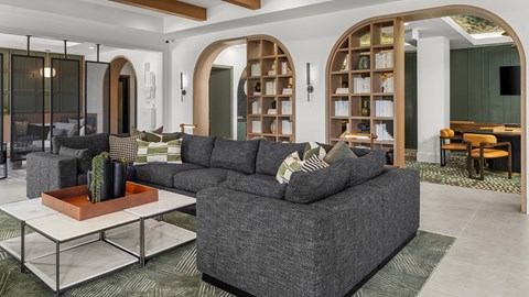 A grey couch with a cactus in a brown pot on a glass table.