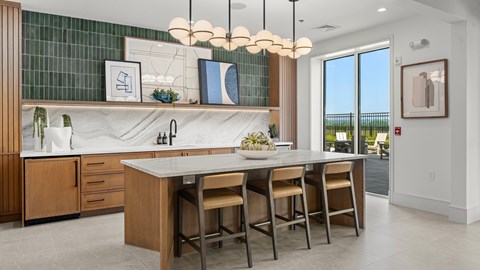A kitchen with a marble countertop and wooden chairs.