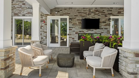 A patio with a stone wall and a flat screen TV mounted on it.