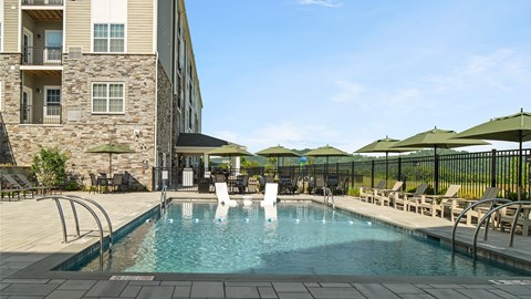 A woman is standing in a pool surrounded by chairs and umbrellas.