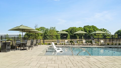 A pool area with a table and chairs and umbrellas.