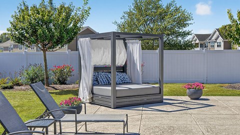 A hot tub is surrounded by a white fence and a few plants.