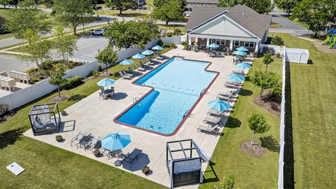 A large outdoor swimming pool surrounded by lawn chairs and umbrellas.
