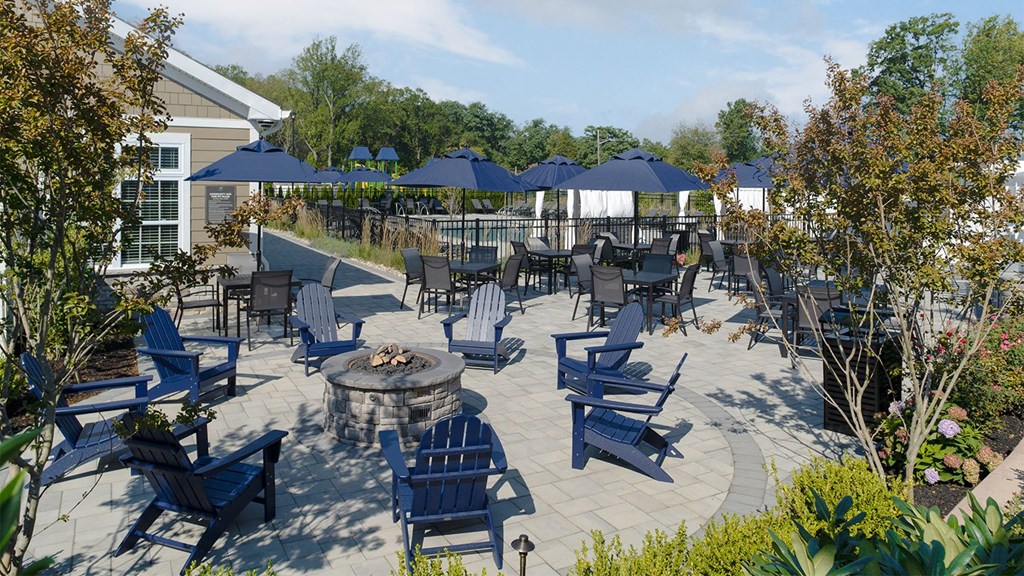 a patio with blue chairs and umbrellas and a fire pit