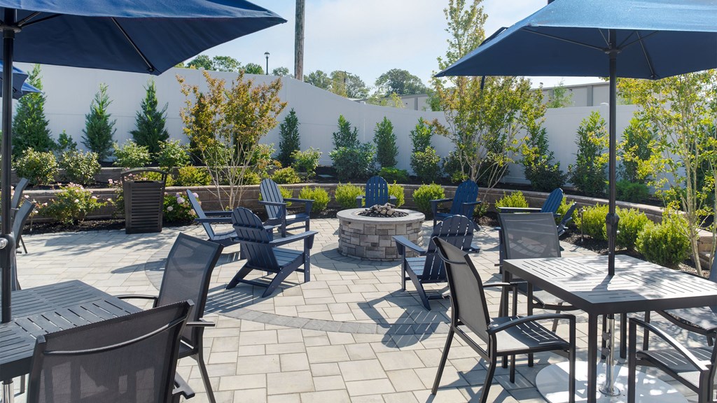 a patio with tables and chairs and a fire pit