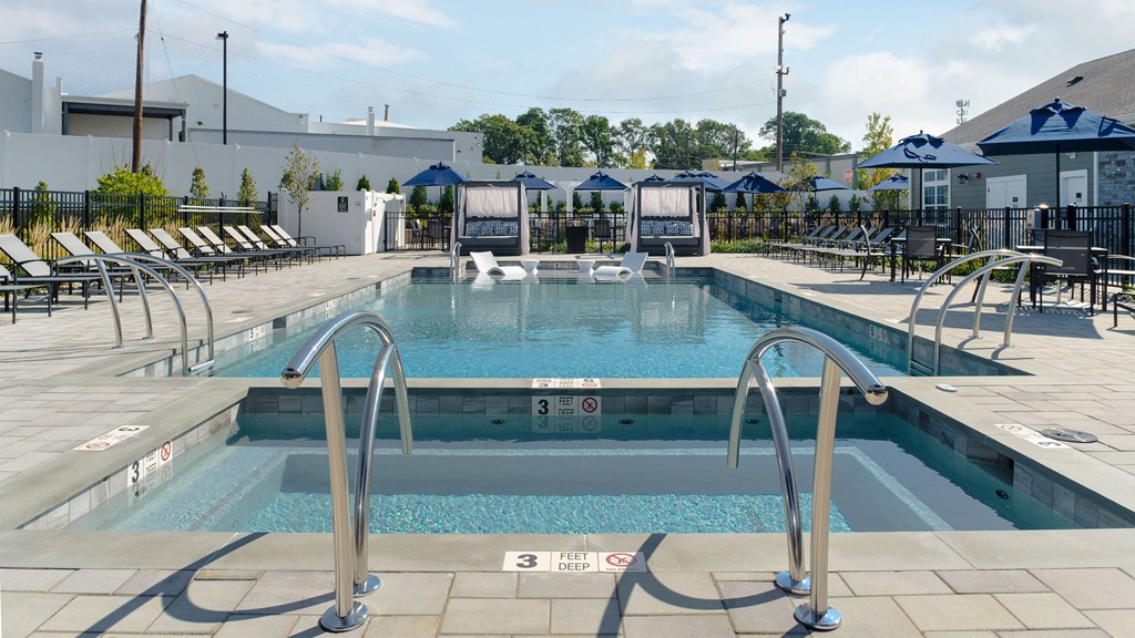 a swimming pool with chairs around it and a building in the background