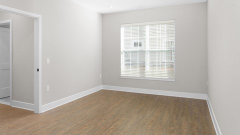A room with a wooden floor and a window with blinds.