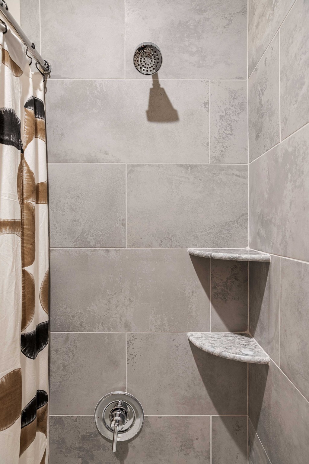 a shower in a tiled bathroom with a shower curtain