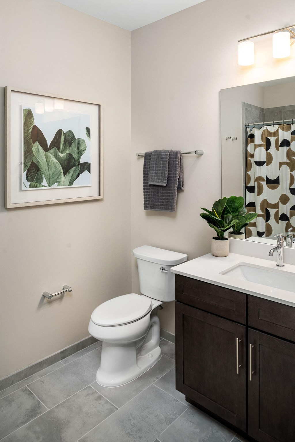 a bathroom with a toilet sink and mirror and a plant