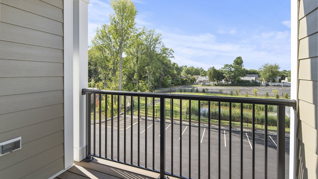 a balcony with a view of a pond and trees