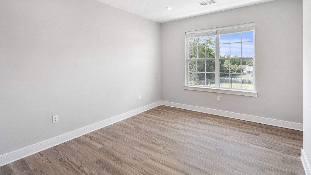 an empty room with wood floors and a window