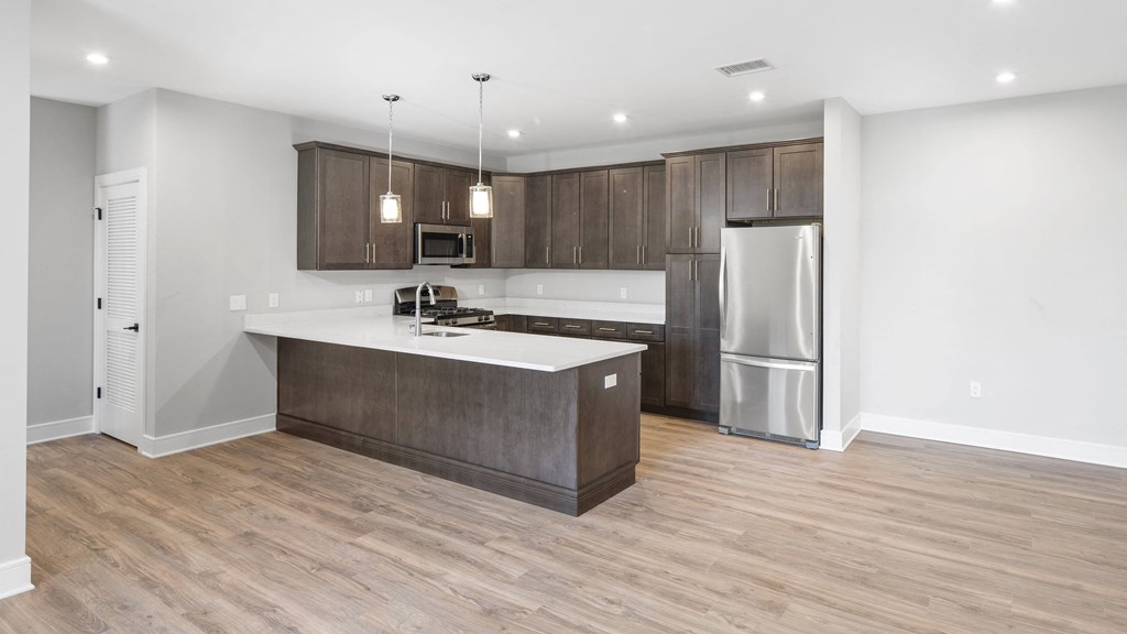 a kitchen with a large island and a stainless steel refrigerator