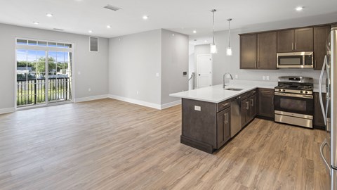 an open kitchen and living room with wood flooring and a window