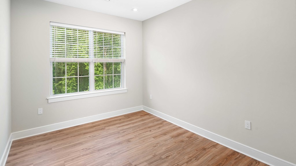 an empty room with wood floors and a window