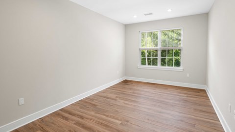 an empty room with wood floors and a window