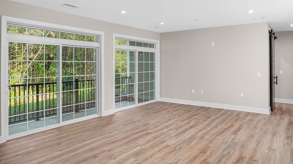 an empty living room with a wood floor and glass doors