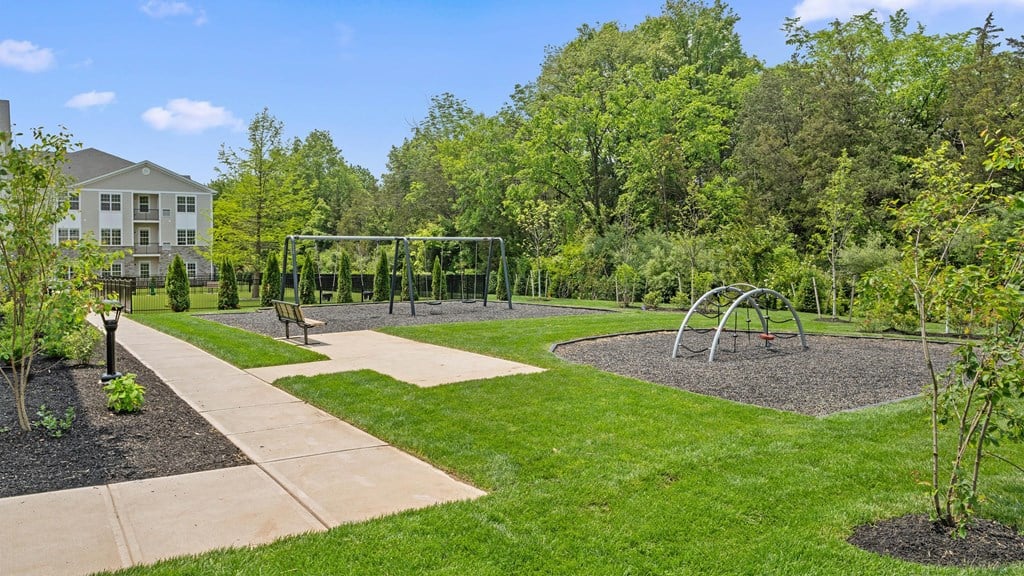a park with a playground and trees with a building in the background