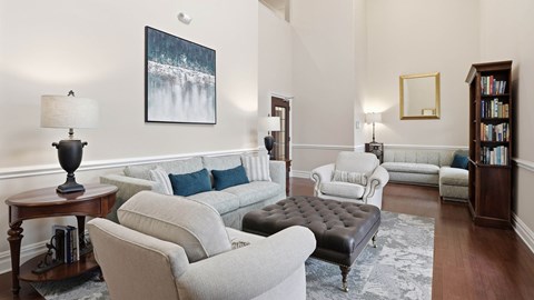 A living room with a grey couch and a black ottoman.