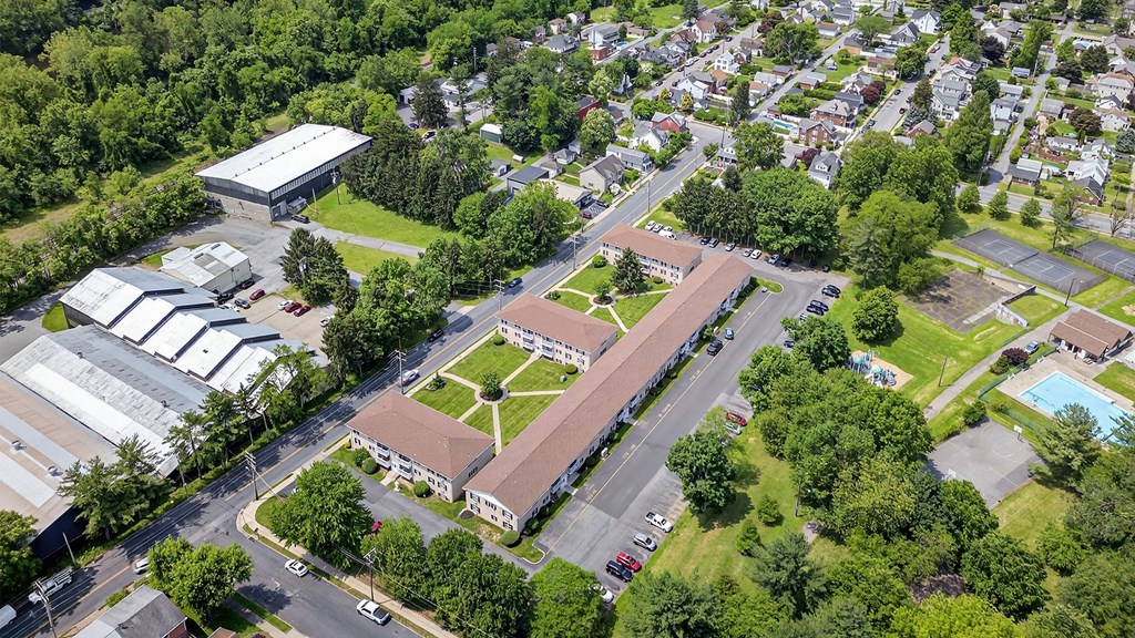 An aerial view of a large building complex surrounded by trees and a parking lot.