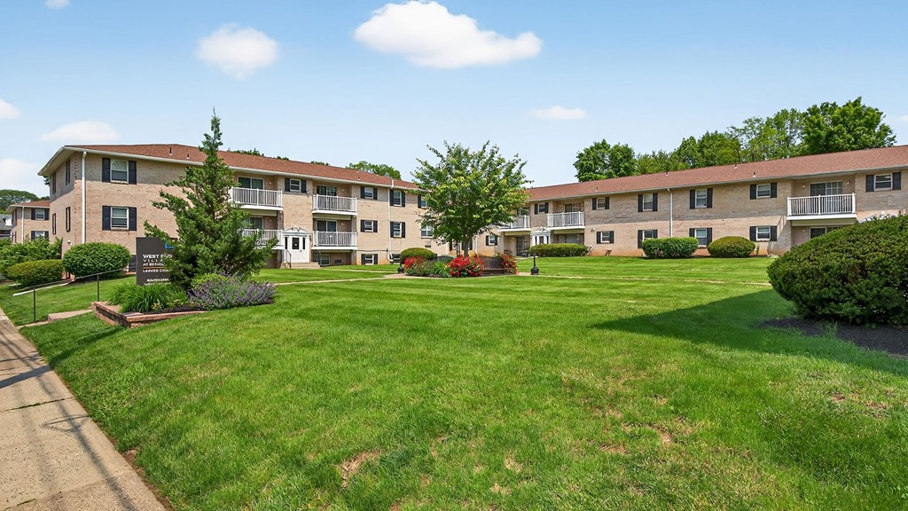 Apartment complex with green lawn and trees.