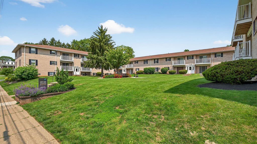 A sunny day at a residential complex with apartment buildings and green lawns.