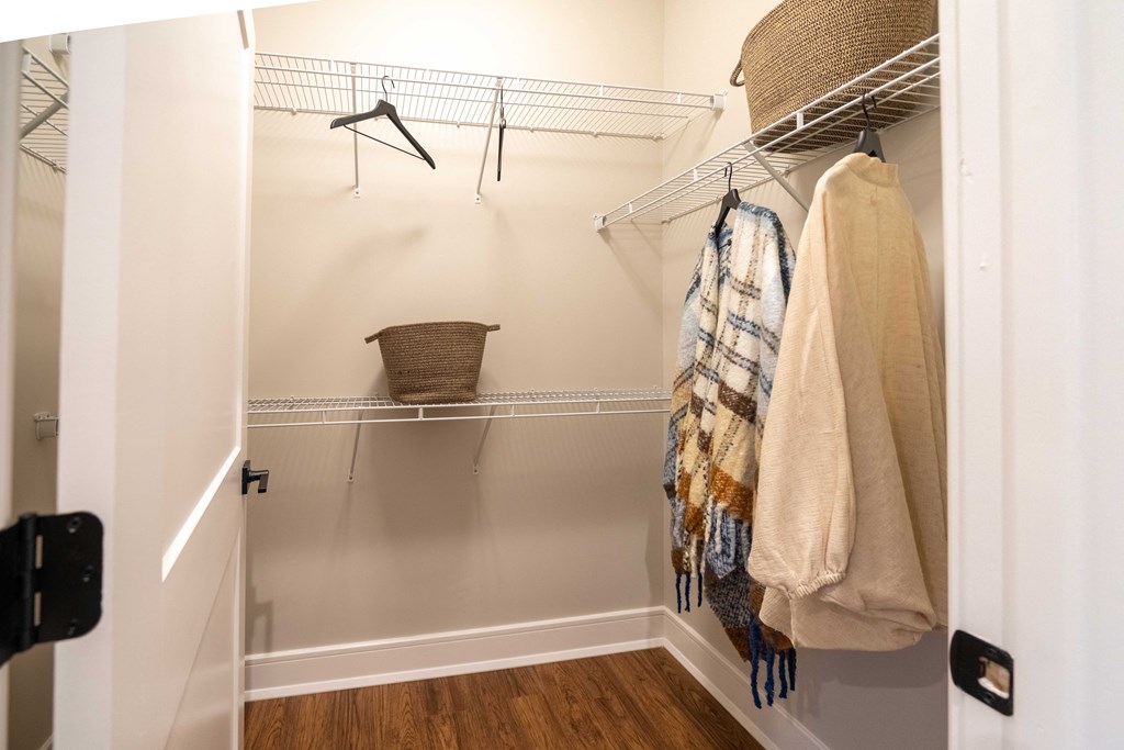 a walk in closet with a rack of clothes and a basket on the wall