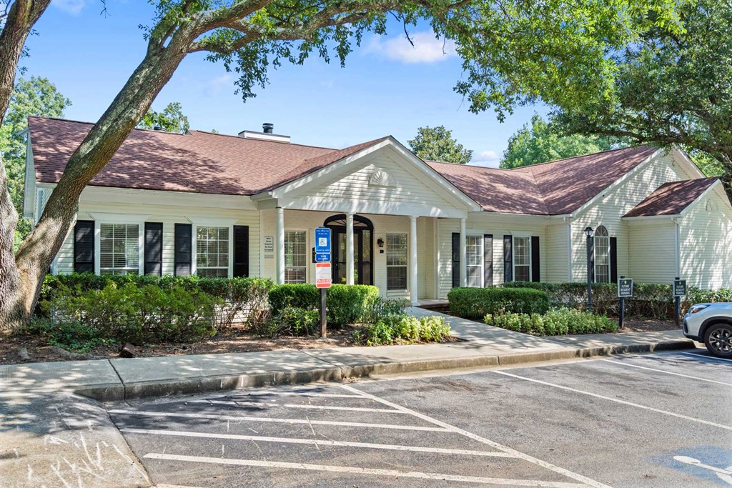a white house with a parking lot and a tree