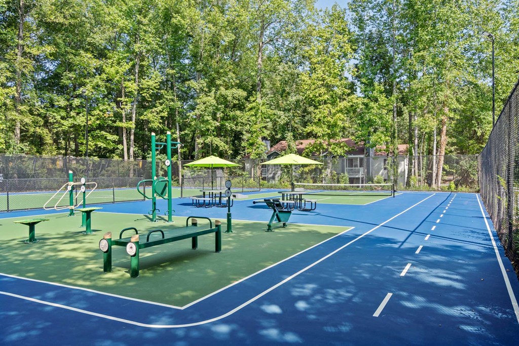 a tennis court with benches and umbrellas on it
