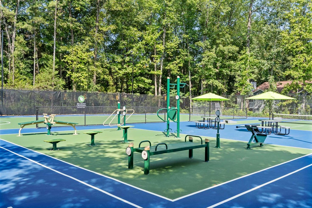 a playground on a tennis court with benches and umbrellas