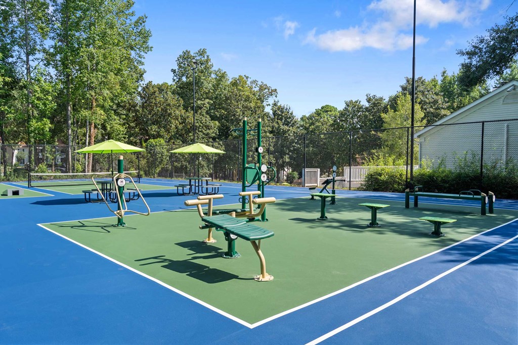 a tennis court with benches and umbrellas on it