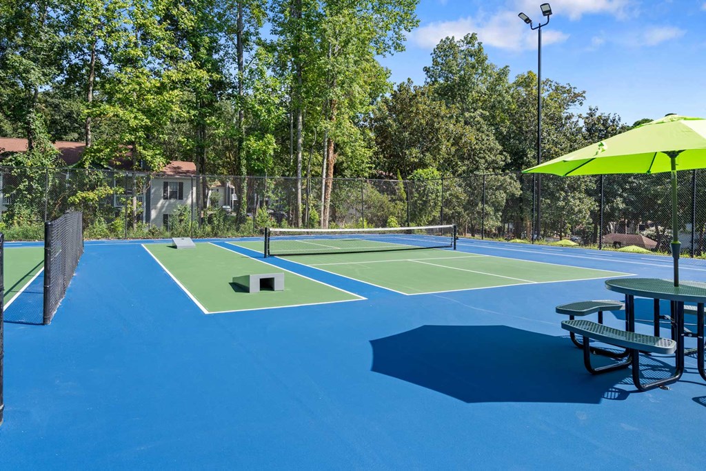 a tennis court with a picnic table and an umbrella