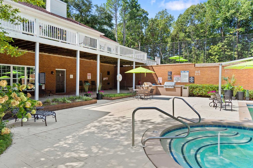 a swimming pool and patio in front of a building with a resort style pool