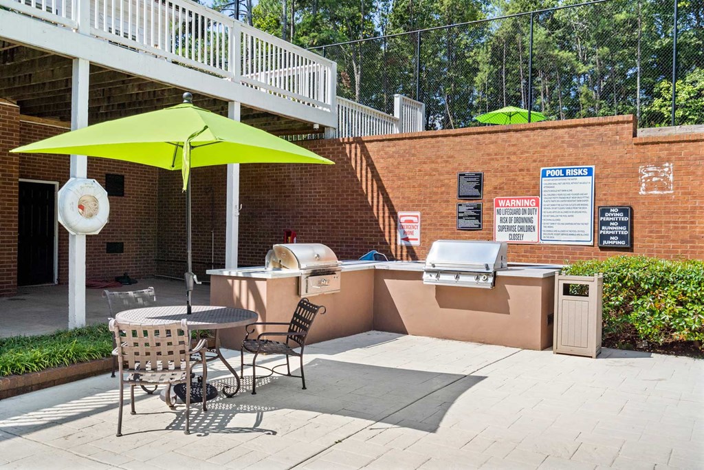 a patio with a grill and a table with chairs