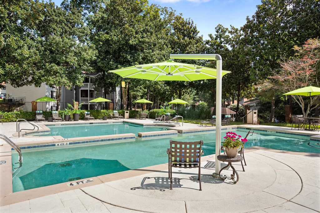a swimming pool with two chairs and an umbrella next to a pool