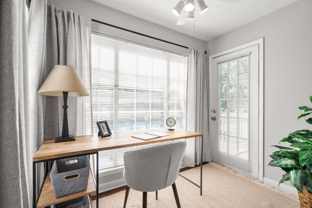 a home office with a window and a desk with a chair and a lamp