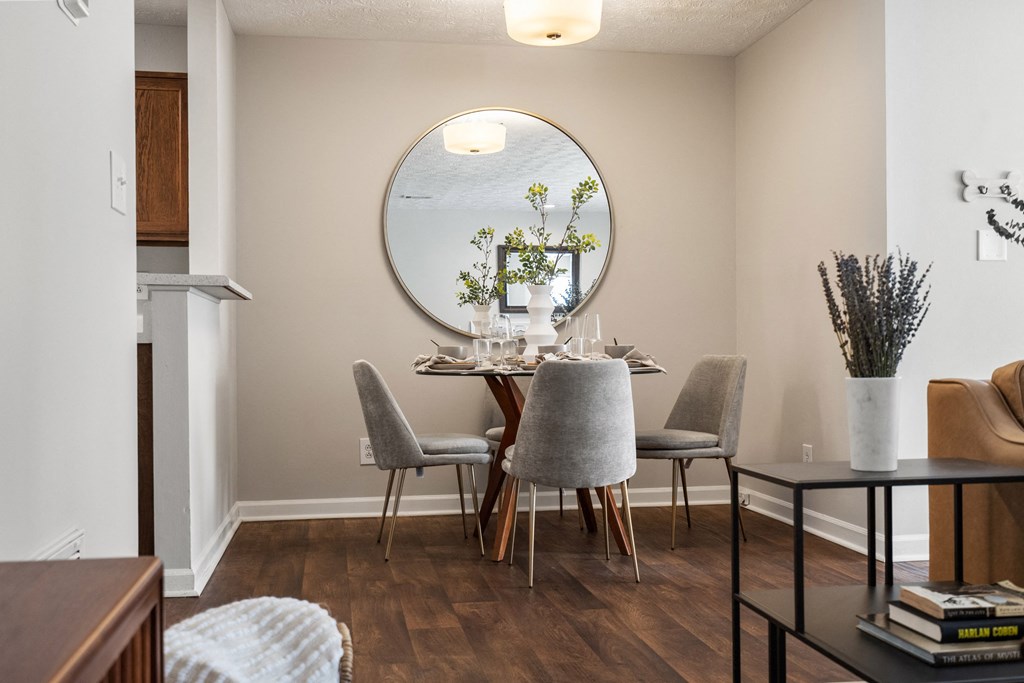 a dining room with a round mirror and a table with chairs