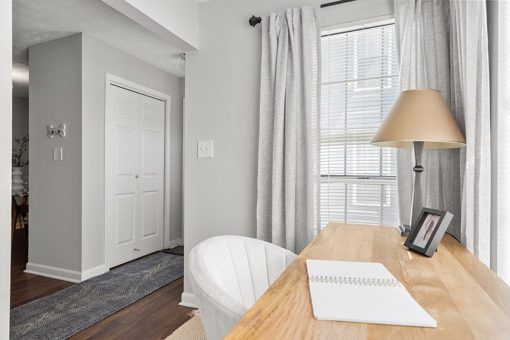 a home office with a desk and a lamp and a window