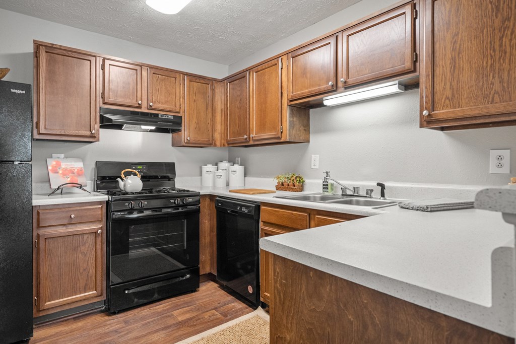a kitchen with wood cabinets and black appliances and white counter tops