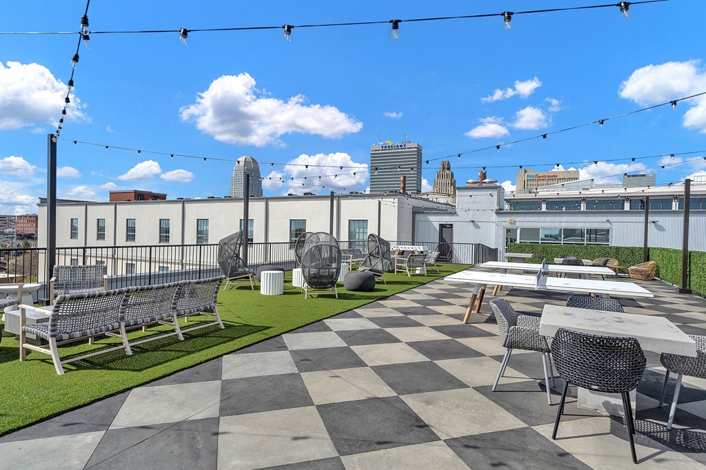 a rooftop patio with tables and chairs and a city in the background