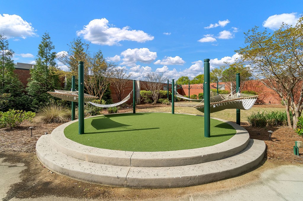 a playground with hammocks and grass on a sunny day