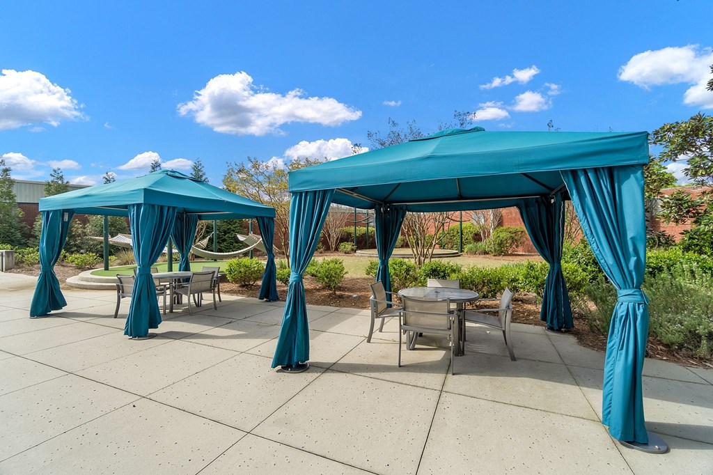 a patio with two blue umbrellas and tables with chairs
