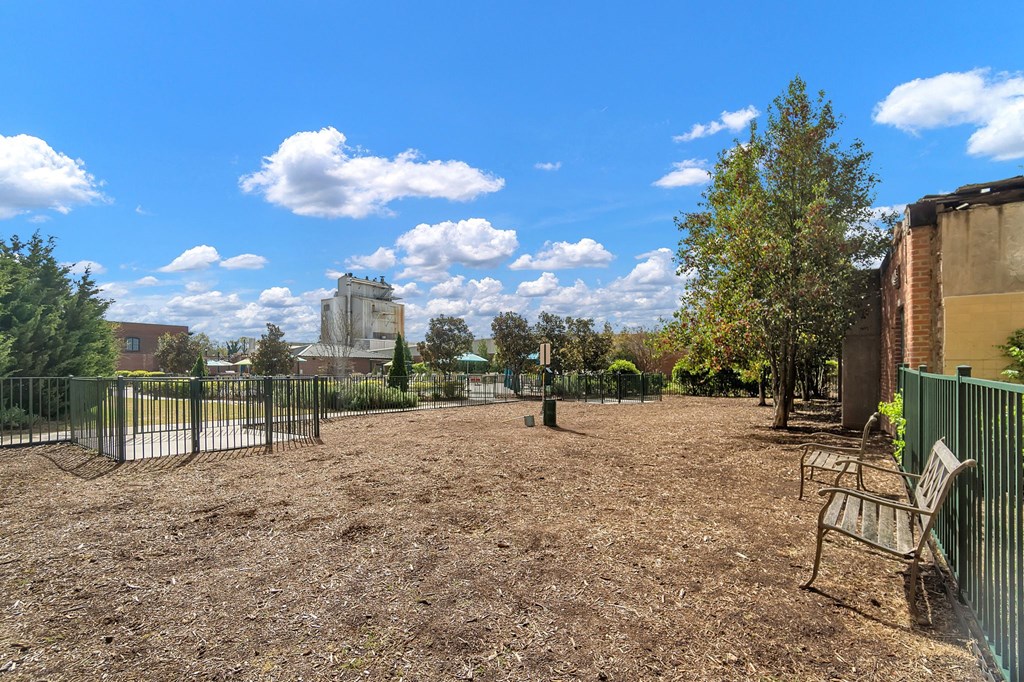 a park with benches and a fence and a building in the background