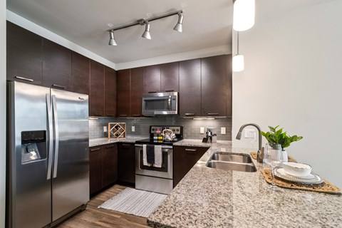 A modern kitchen with dark wood cabinets and stainless steel appliances.