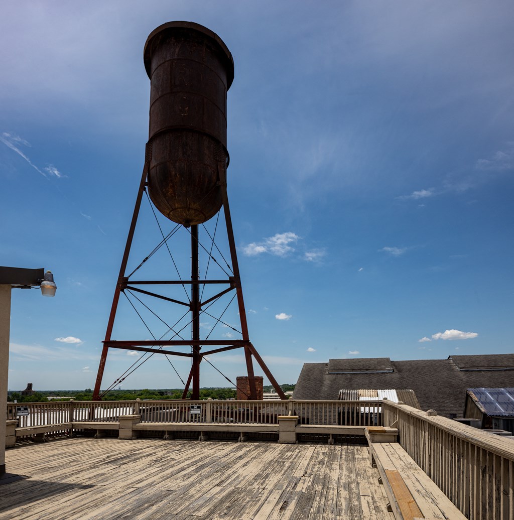 a water tower on top of a wooden deck in front of a building