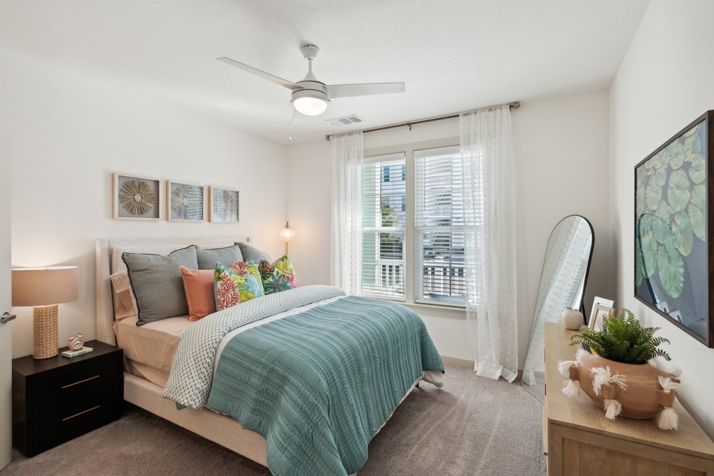 A bedroom with a bed, nightstand, and a ceiling fan.
